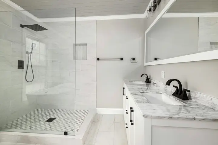 Walk-in shower with marble-look walls, mosaic floor and a vanity with matte black faucet