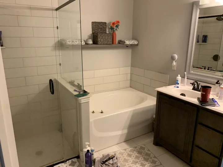 The same bathroom before: subway tile shower, jetted tub and dark vanity