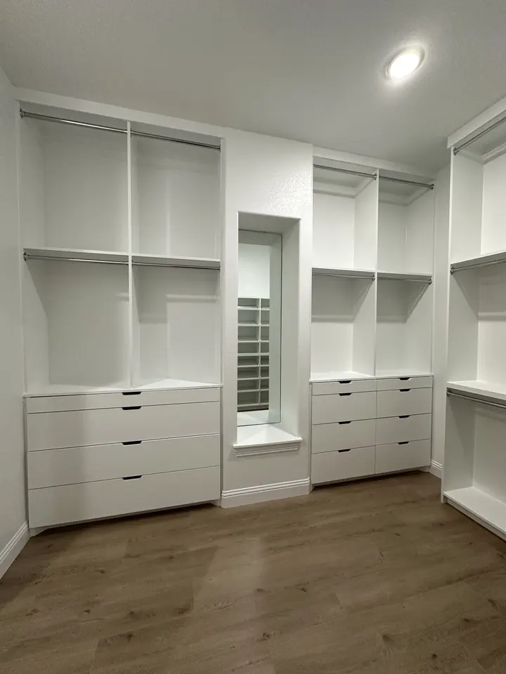 White walk-in closet system with drawer banks, open shelving and a mirror niche
