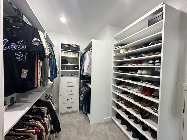 Walk-in closet with a floor-to-ceiling shoe wall, drawers and hanging space