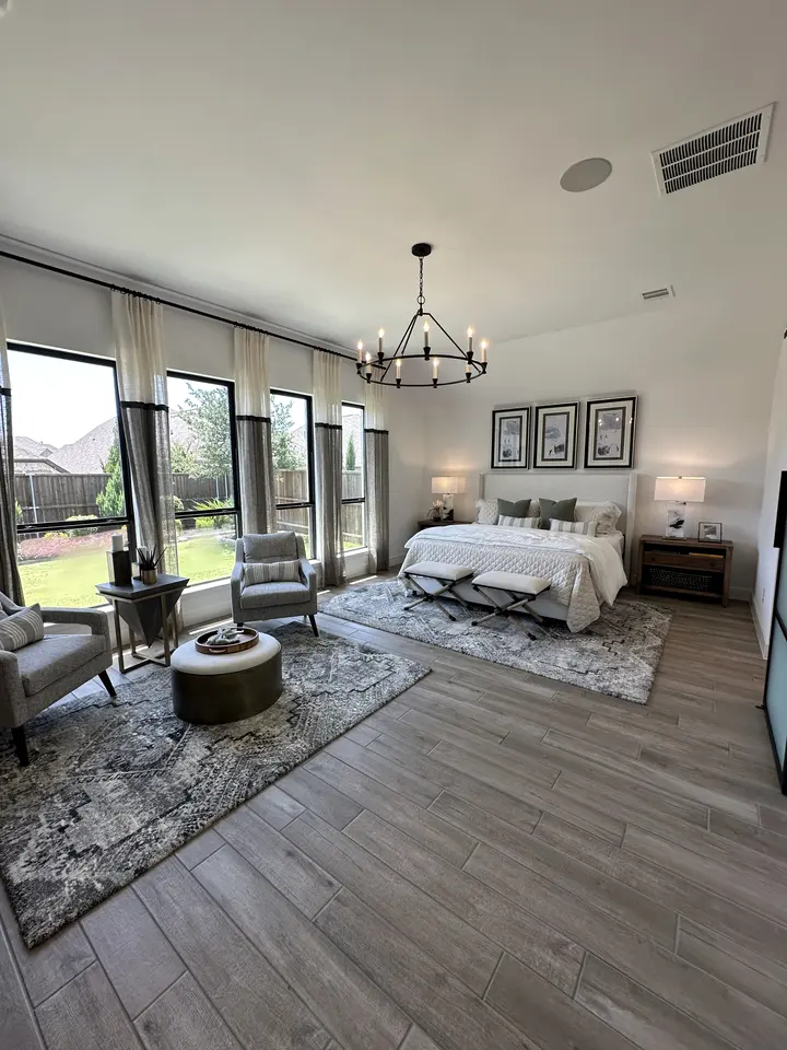 Bedroom with wood-look plank flooring, tall windows and a black chandelier
