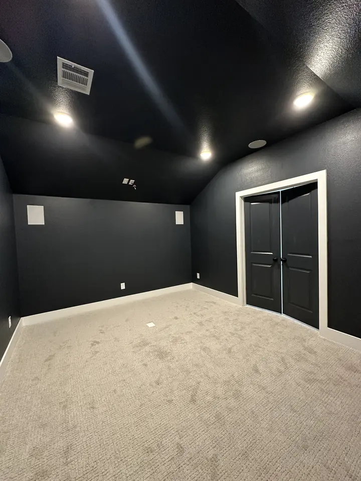Finished media room with deep navy walls and ceiling and white trim